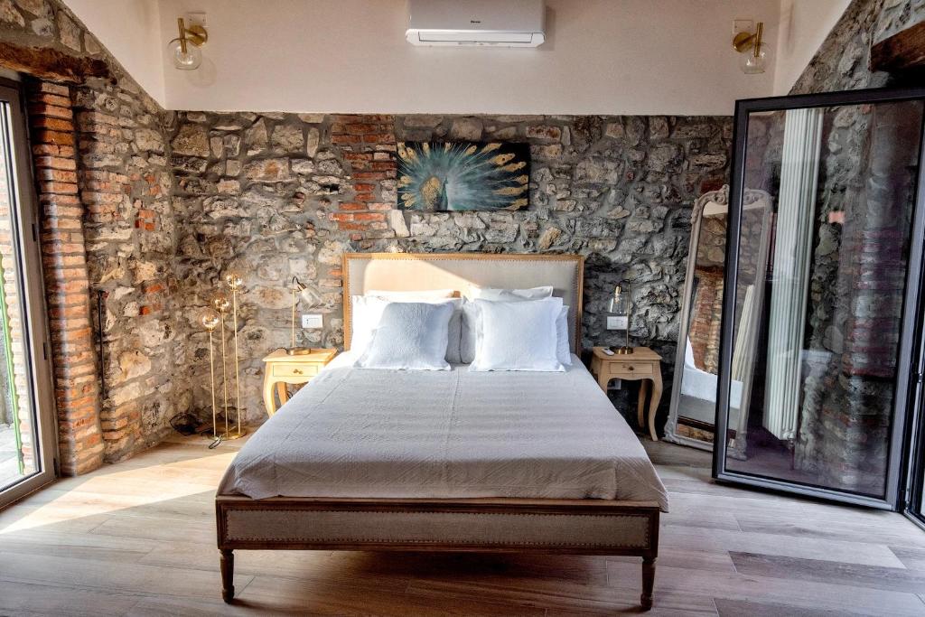 Lora Lake Villa في Ossuccio: غرفة نوم بسرير وجدار حجري