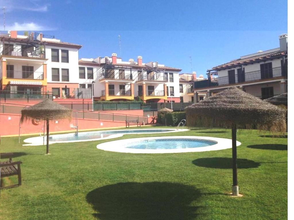 una piscina en un patio con sombrillas en el césped en Costa Esuri Golf y Playa IV, en Ayamonte