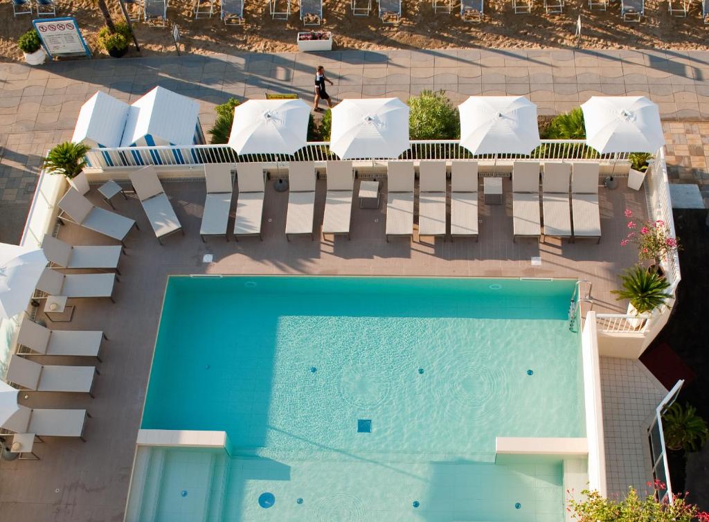 una vista aérea de una piscina con sillas y mesas blancas en Hotel Canarie, en Lido di Jesolo