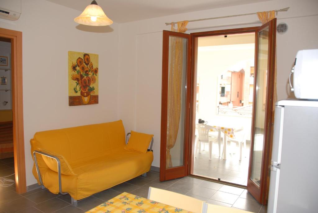 uma sala de estar com um sofá amarelo e uma porta de vidro deslizante em I Portici Apartments em Marina di Grosseto
