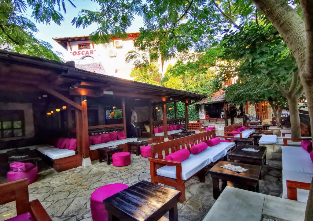 a restaurant with benches and tables and pink chairs at Pansion Oscar Summer Garden in Mostar