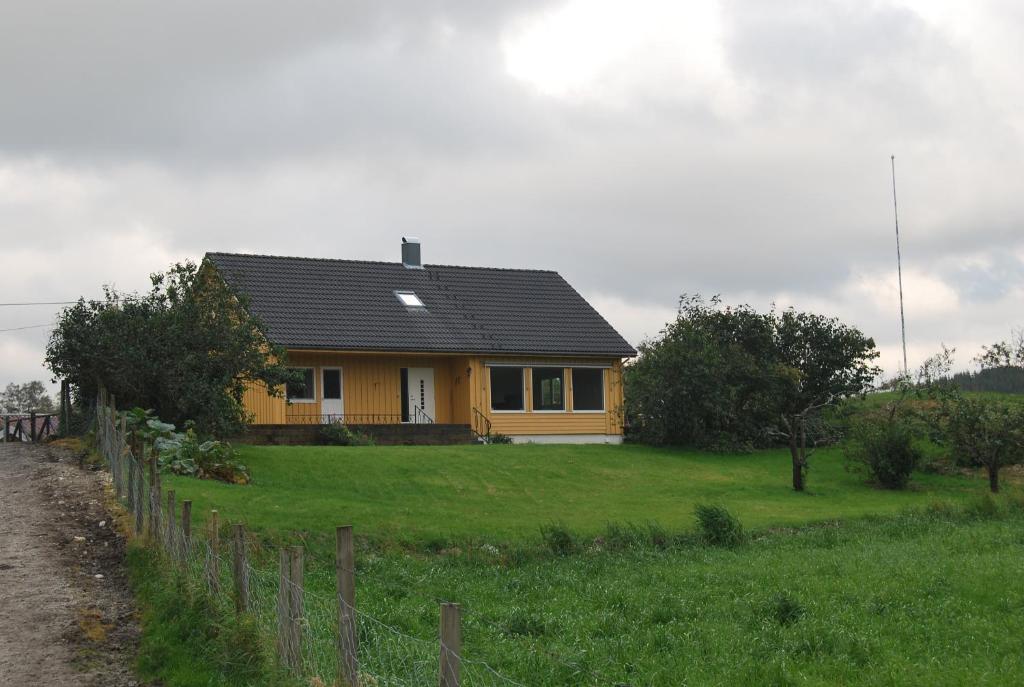 Bjerkreim的住宿－艾克蘭德加爾德酒店，绿色田野上黑色屋顶的黄色房子