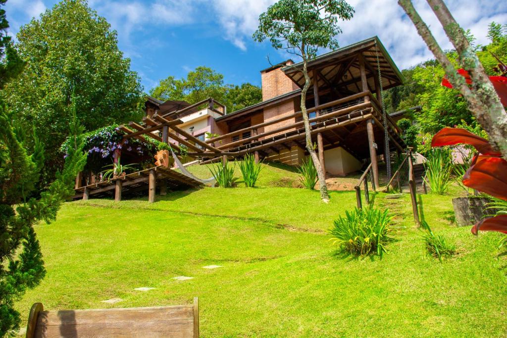 uma casa num jardim relvado com um edifício em Pousada Vinhas do Pinhal em Santo Antônio do Pinhal