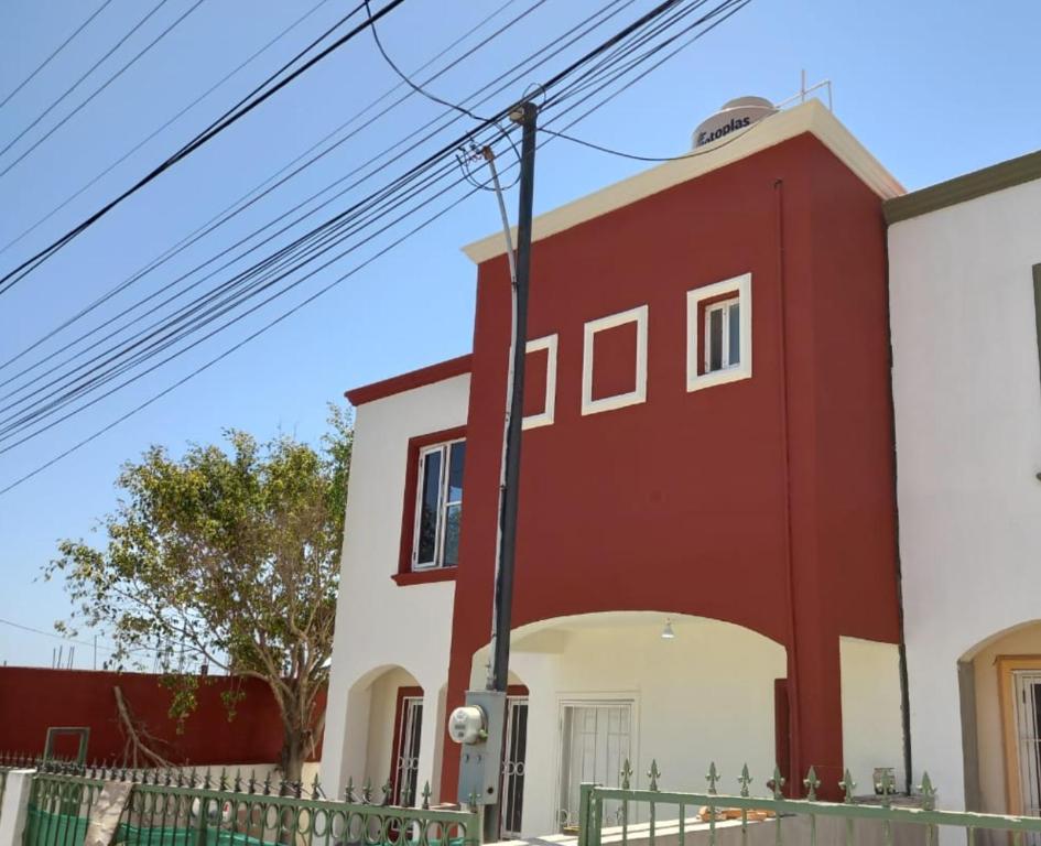 a red and white building with a fence at Montecarlo 2 in Rosarito