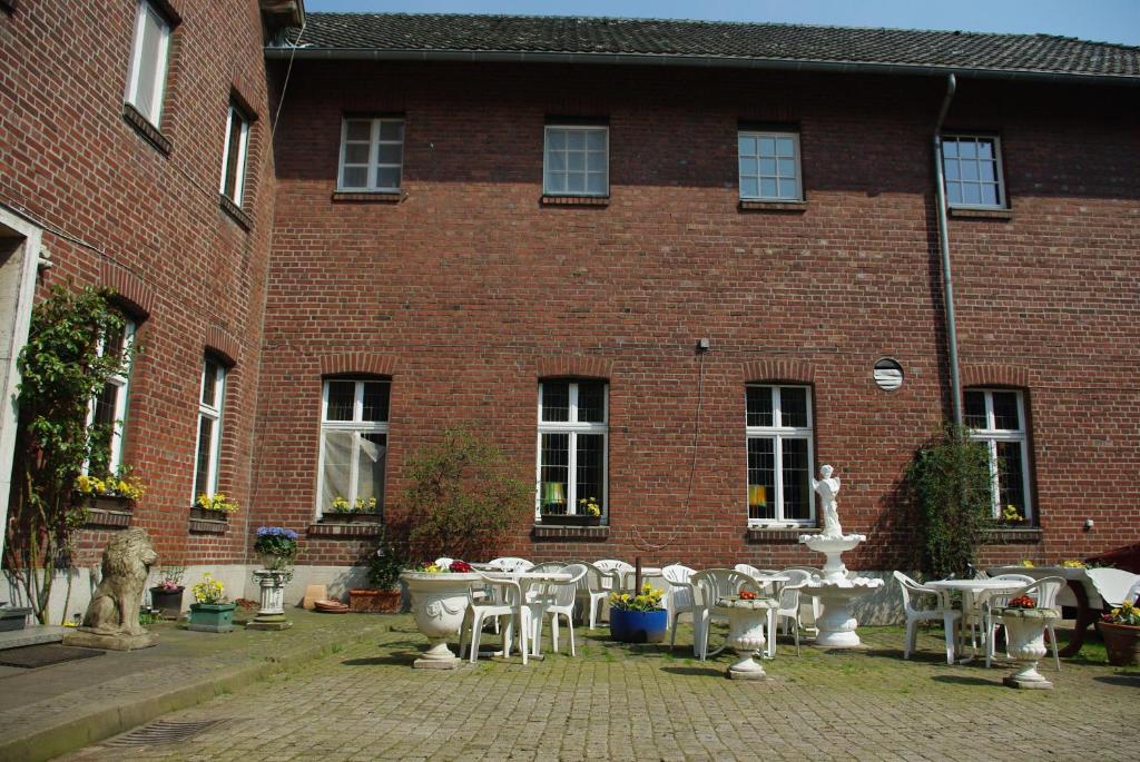 un bâtiment en brique avec des tables et une fontaine devant lui dans l'établissement Pension Genengerhof, à Viersen