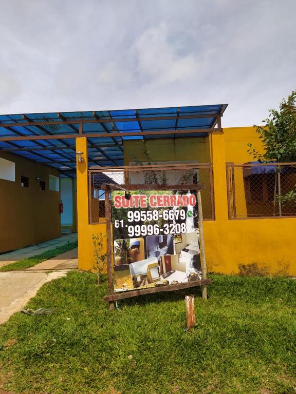 a sign in the grass in front of a yellow building at Suites Cerrado in Alto Paraíso de Goiás