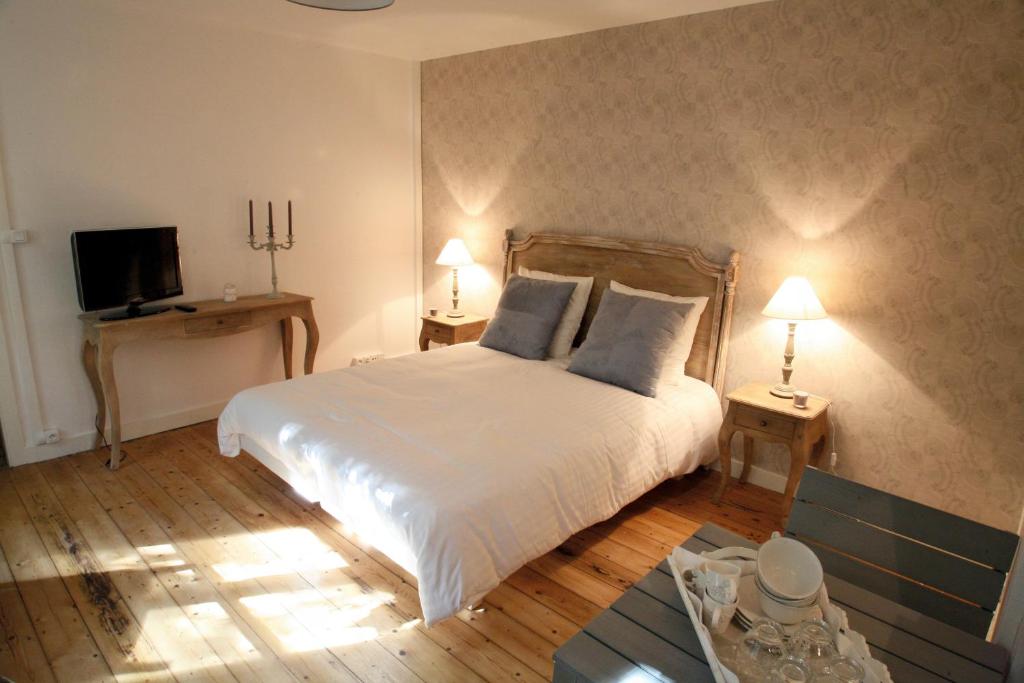 1 Schlafzimmer mit einem weißen Bett mit 2 Tischen und einem TV in der Unterkunft Appartements Orfèvres Cathédrale in Straßburg