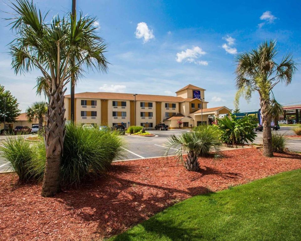 a large building with palm trees in front of it at Sleep Inn McDonough in McDonough