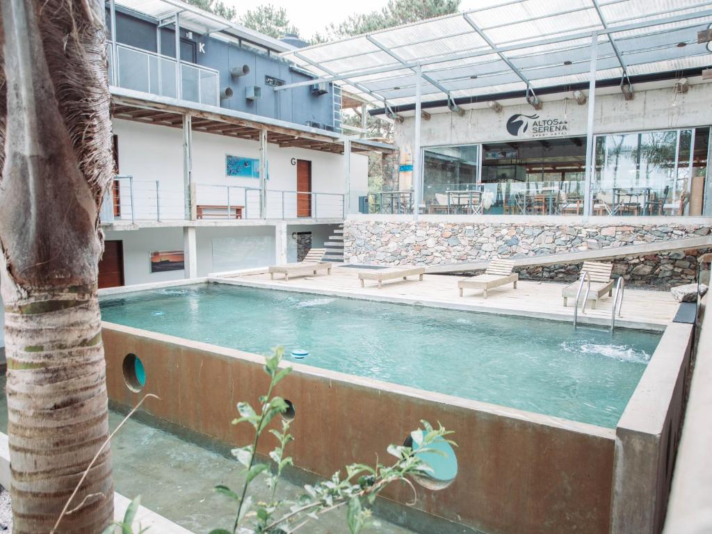 a swimming pool with a palm tree in front of a building at Altos de la Serena Apart Hotel in La Paloma