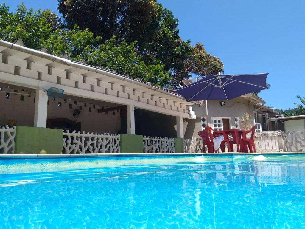 a house with a swimming pool and an umbrella at Pousada Nova Primavera in Ubatuba