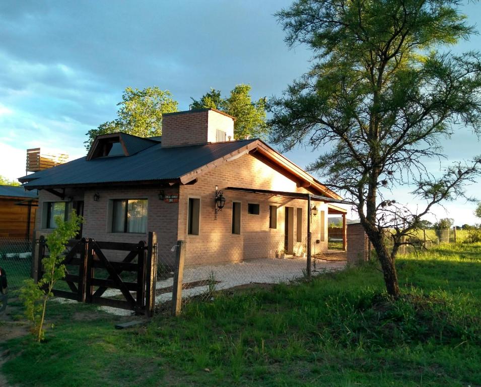 a small house in a field with a tree at Atardecer Serrano in Villa General Belgrano