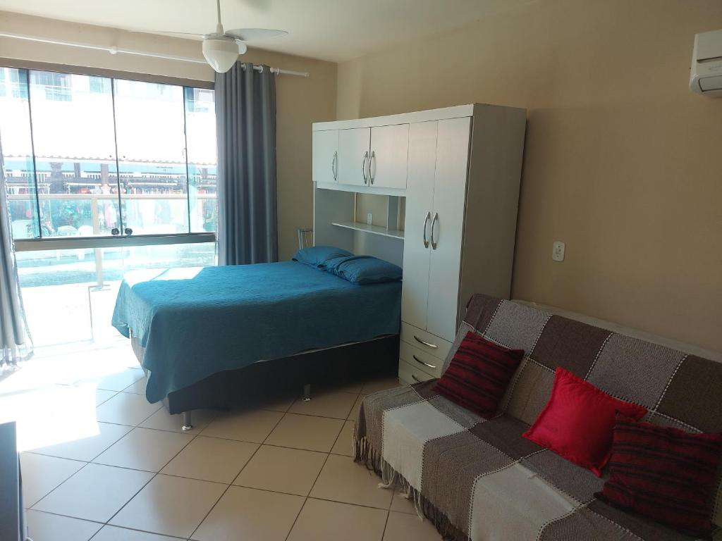 1 dormitorio con cama, sofá y ventana en loft Prainha, en Arraial do Cabo