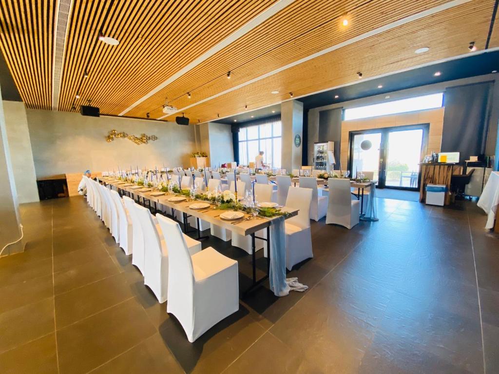 a long dining room with white tables and white chairs at SkyeBay Club in Hengchun