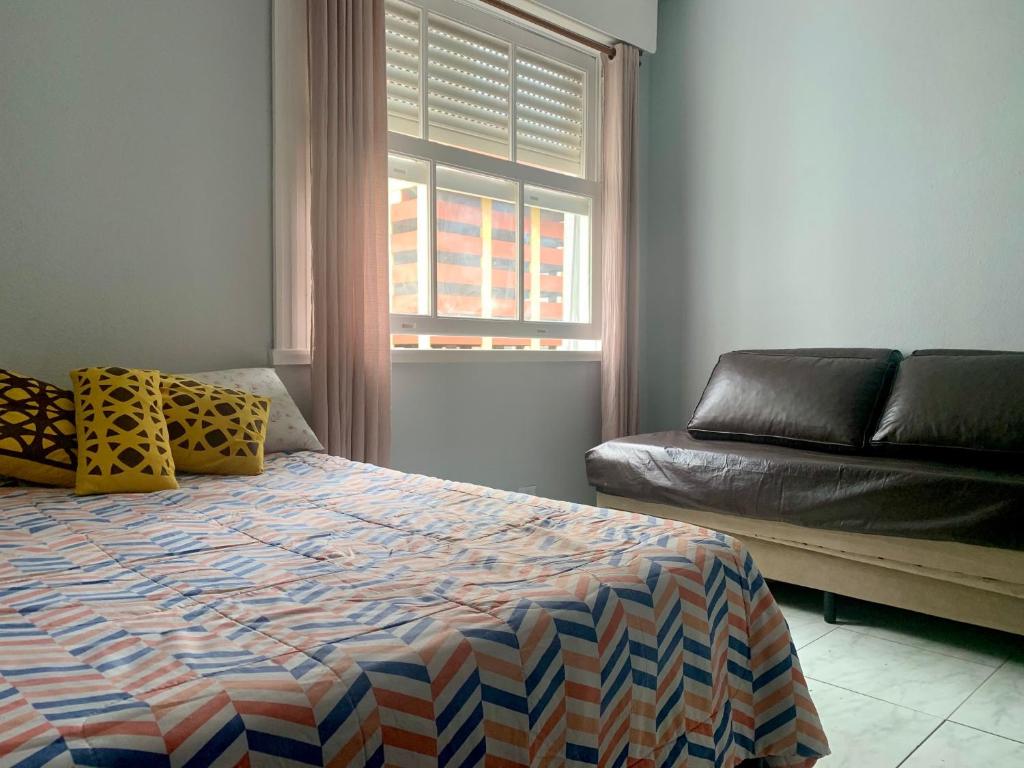 um quarto com uma cama, um sofá e uma janela em Pitangueiras Guarujá Apto com garagem no Guarujá