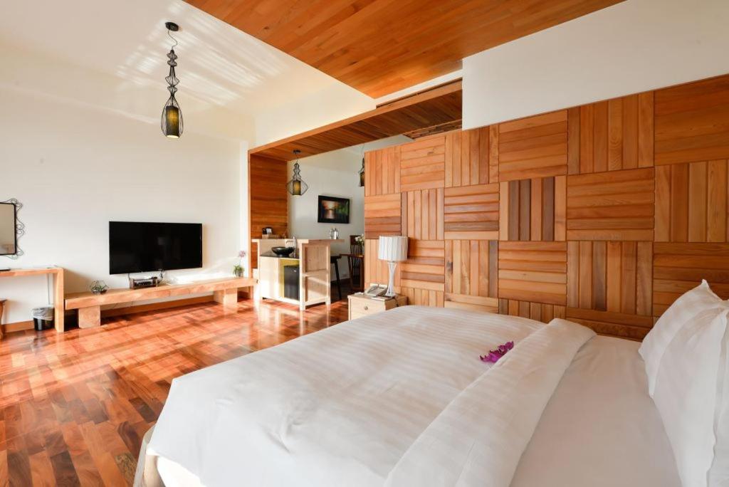 a bedroom with a white bed with a wooden wall at Bay Forest Boutique B&amp;B in Hengchun South Gate
