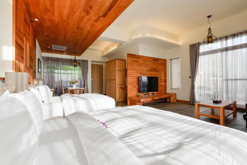 a bedroom with a white bed and a television at Bay Forest Boutique B&amp;B in Hengchun South Gate