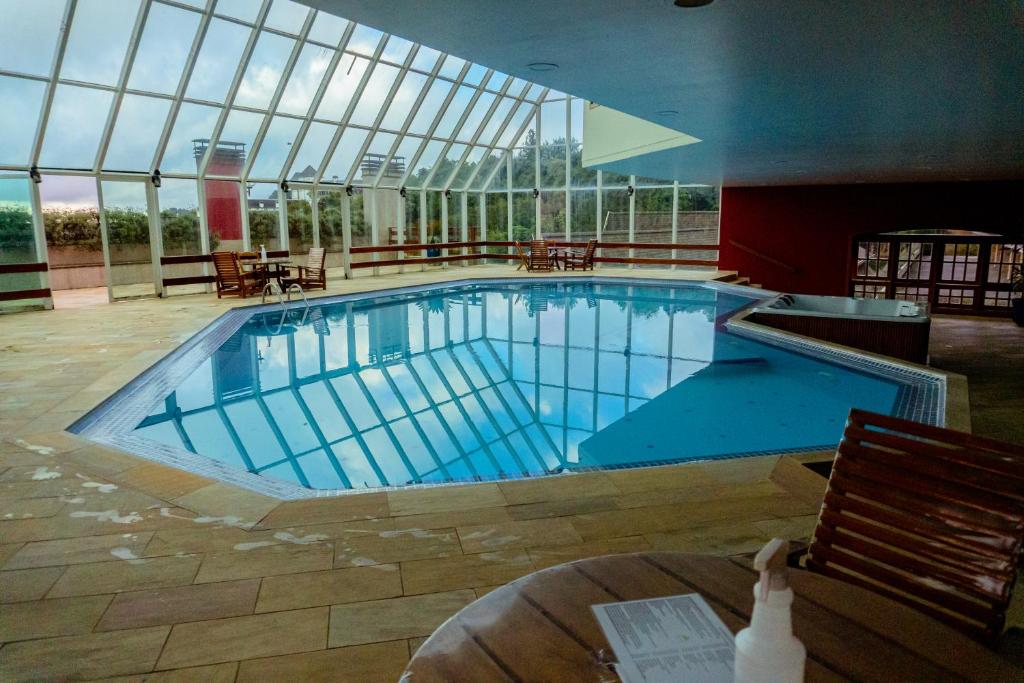 una gran piscina en un edificio con una gran ventana en Quatre Saisons Residence, en Campos do Jordão