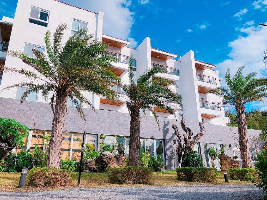 a building with palm trees in front of it at Bay Forest Boutique B&amp;B in Hengchun South Gate