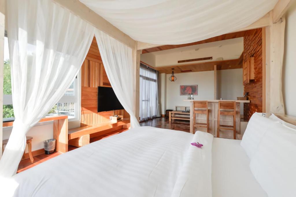 a bedroom with a white bed and a kitchen at Bay Forest Boutique B&amp;B in Hengchun South Gate