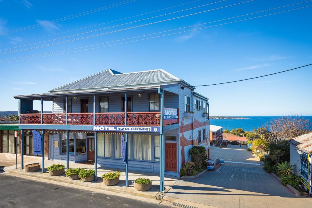 a blue building on a street with the ocean in the background at Heritage House Motel & Units in Eden