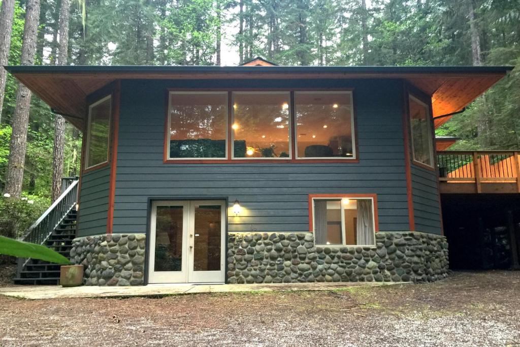 ein kleines blaues Haus mit einer Steinmauer in der Unterkunft Snowline Cabin #29 - An Ultra Custom Family Vacation Home! in Glacier