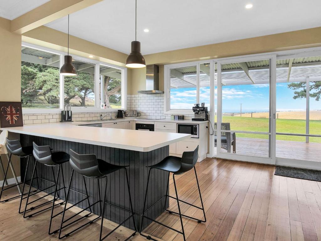a kitchen with a large island with bar stools at Kilcunda Coast House in Woolamai