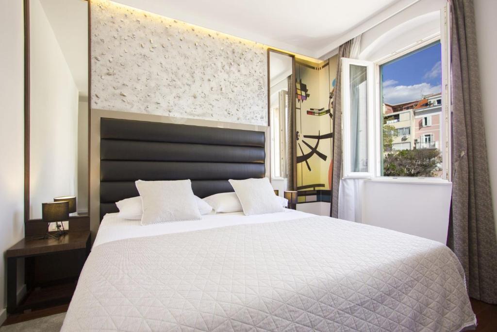 ein Schlafzimmer mit einem großen weißen Bett und einem Fenster in der Unterkunft Argentum Luxury Apartment in Split