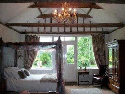 ein Schlafzimmer mit einem Himmelbett und einem großen Fenster in der Unterkunft The Walnuts Country House in West Row