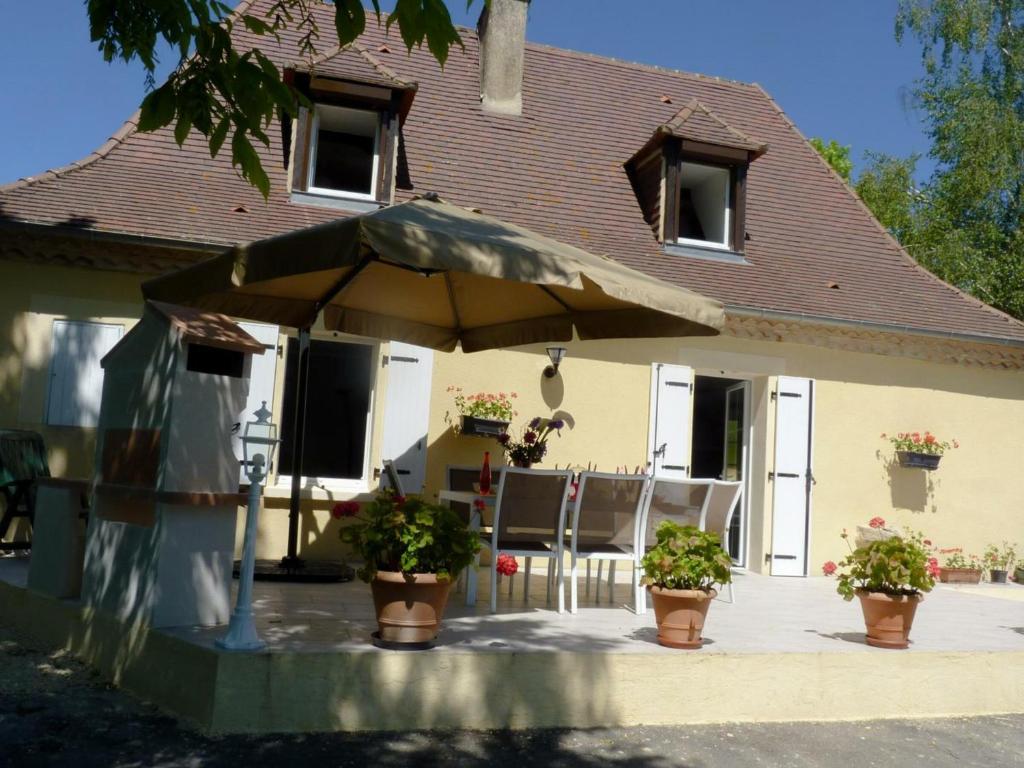 a patio with an umbrella in front of a house at Gîte Cendrieux, 5 pièces, 7 personnes - FR-1-616-14 in Cendrieux