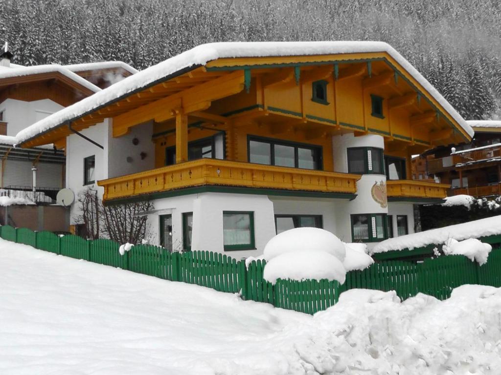 una casa con una valla verde en la nieve en Appartementhaus Zillertal by PiaundDirk, en Finkenberg