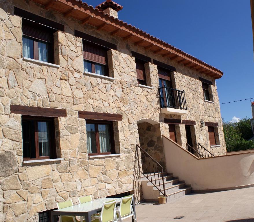 a stone building with two chairs in front of it at Alojamientos Botica Rural in La Cabrera