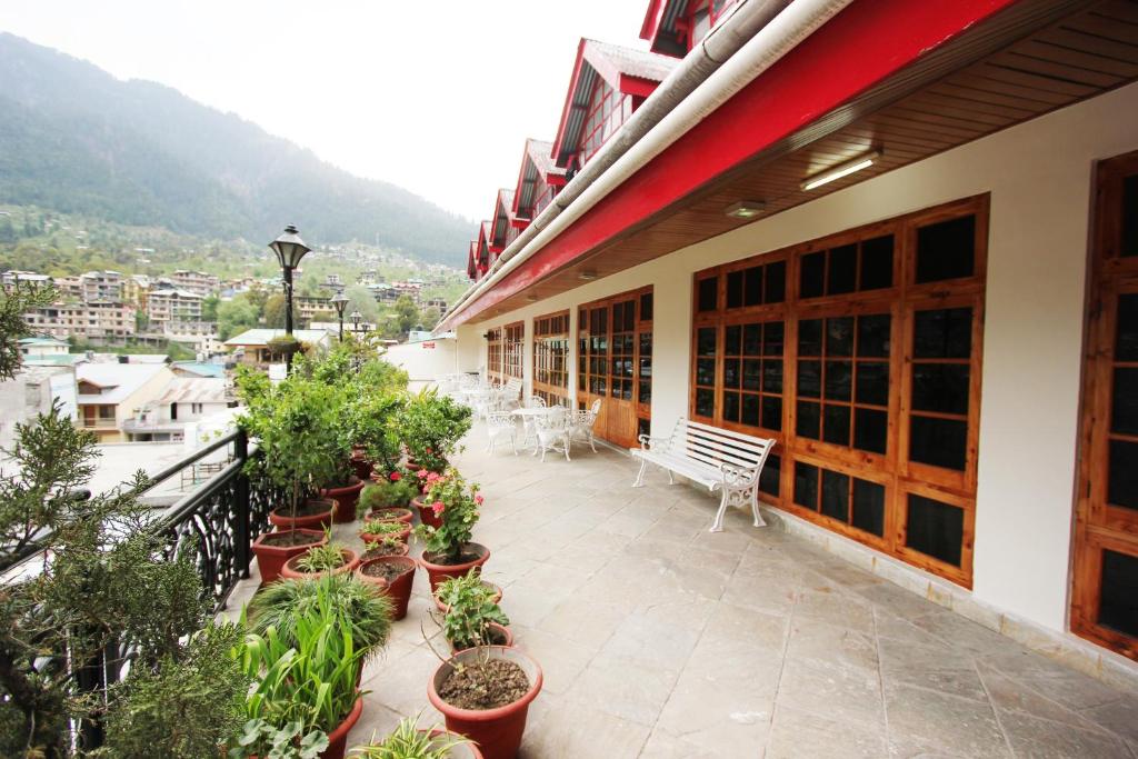 a balcony of a building with chairs and plants at Hotel Snow View Manali in Manāli