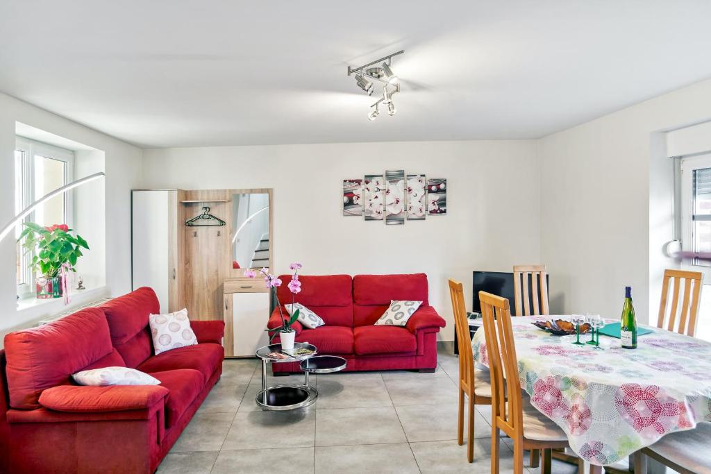 a living room with a red couch and a table at Maison charmante à Stotzheim + jardin in Stotzheim