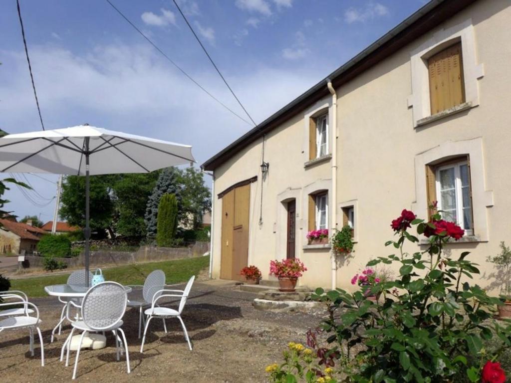 un patio con mesa, sillas y sombrilla en Gîte Chaumont-la-ville, 2 pièces, 2 personnes - FR-1-611-36, 