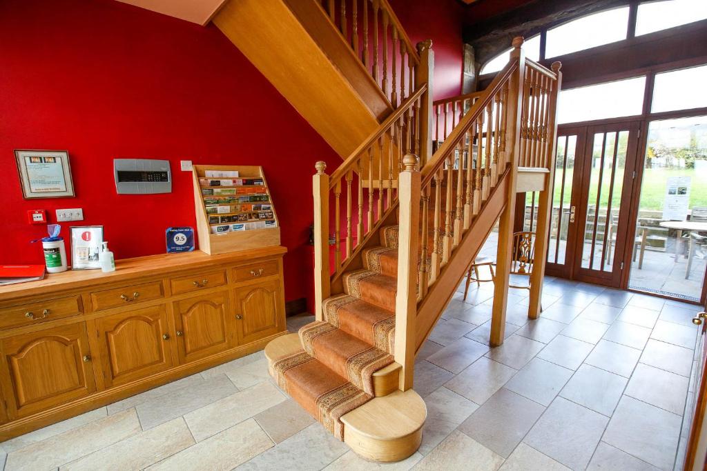 a staircase in a room with a red wall at Padley Farm in Bradfield