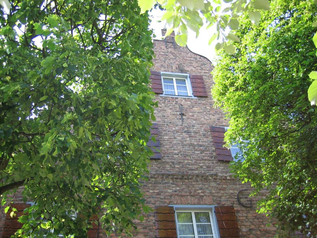 un edificio de ladrillo con dos ventanas y árboles en Hotel Lindenhof, en Mönchengladbach