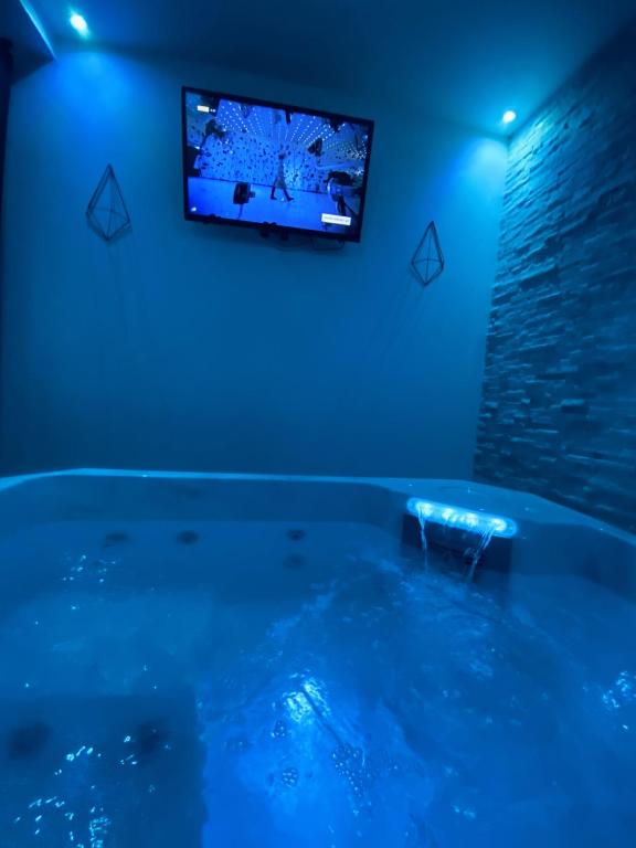 a room with a tub with a tv on the wall at Lh Rooms Location in Le Havre