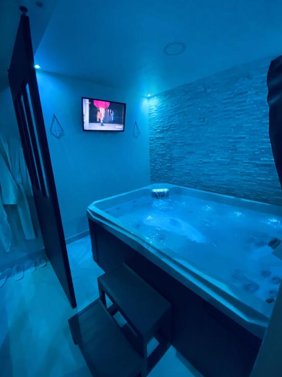 a blue bathroom with a tub and a tv at Lh Rooms Location in Le Havre