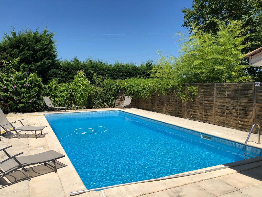 una piscina en un patio con sillas y una valla en La Maison des Brandes, en Eynesse