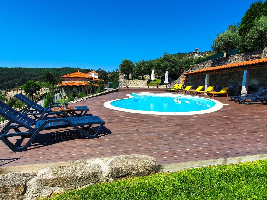 a swimming pool on a wooden deck with chairs around it at Casa em Ponte de Lima in Ponte de Lima
