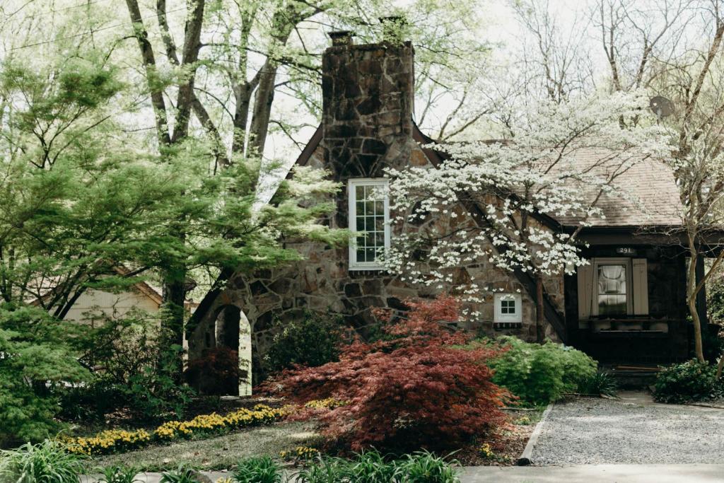 une ancienne maison en pierre avec des fleurs devant elle dans l'établissement The Woodlawn Tudor, à Hot Springs