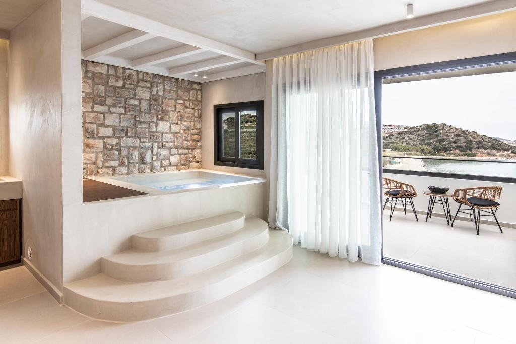 a bathroom with stairs and a tub and a balcony at The Sand Suites - Adults Only in Agios Nikolaos