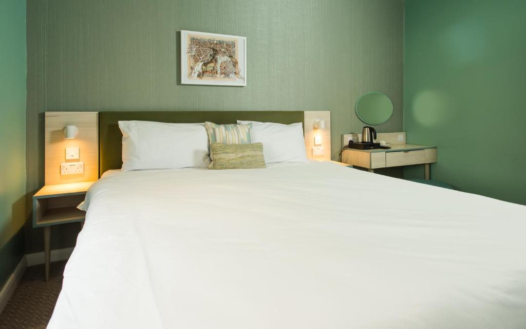 a large white bed in a room with two lamps at Caring Hotel in London