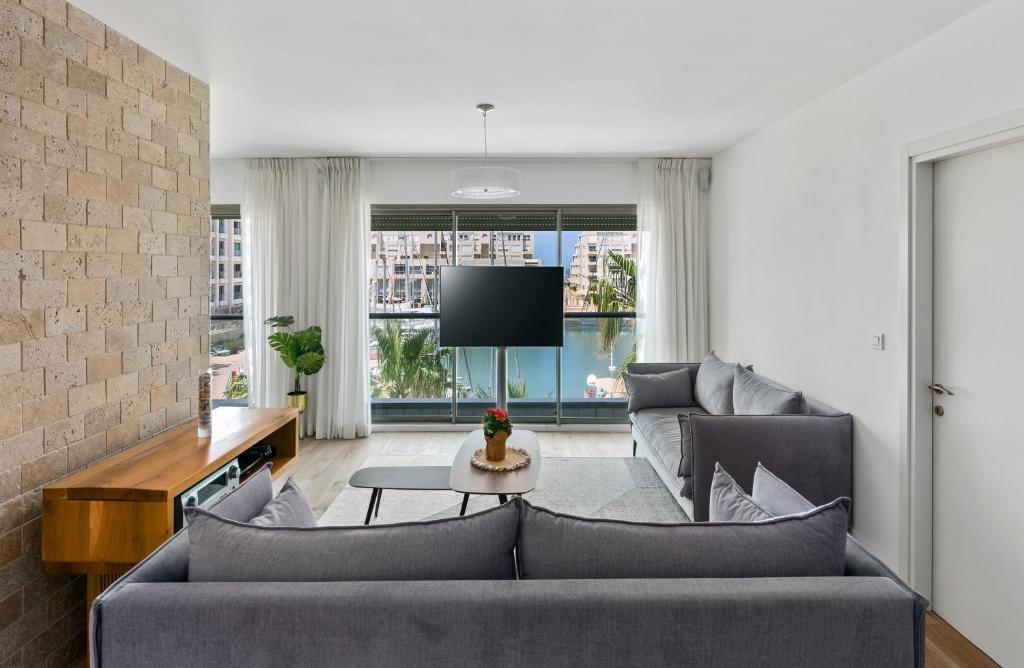 a living room with two couches and a tv at Lagoon Amazing Water Front 3 Bedrooms in Herzliya B