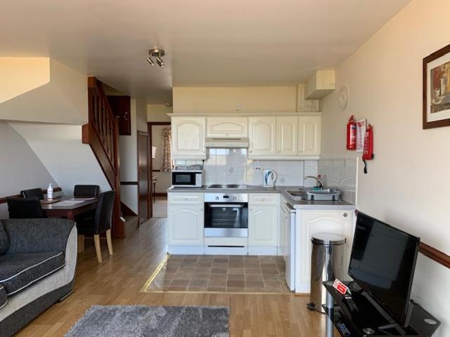 eine Küche mit weißen Schränken und ein Wohnzimmer in der Unterkunft Willow Lakes in Ashby cum Fenby