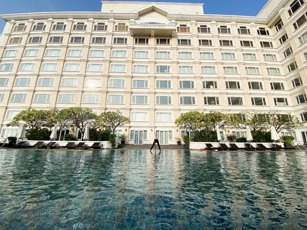 a person walking in front of a large building at Hotel Equatorial Ho Chi Minh City in Ho Chi Minh City