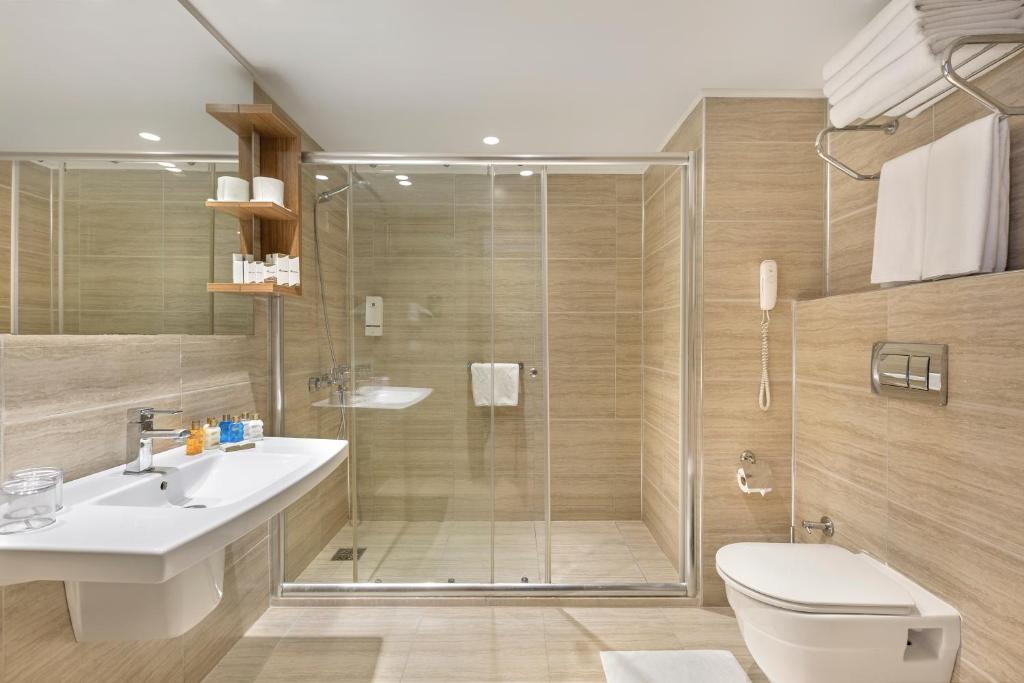a bathroom with a shower and a toilet and a sink at Grand Park Lara Hotel in Lara