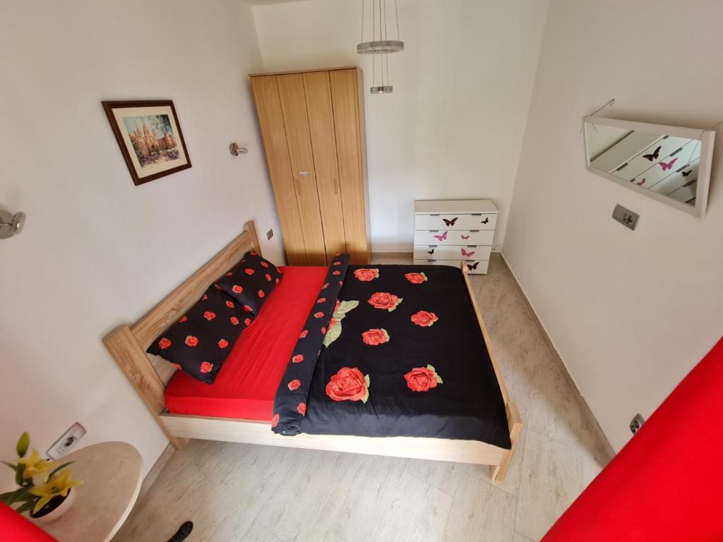 a small bedroom with a bed with red and black sheets at Lux apartmani Darija in Kotor