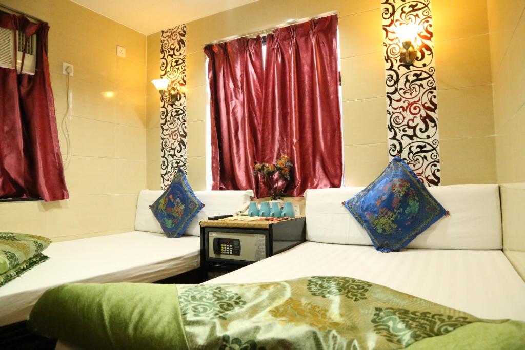 香港にあるオーストラリアン ゲスト ハウスの赤いカーテンが備わるドミトリールームのベッド2台分です。