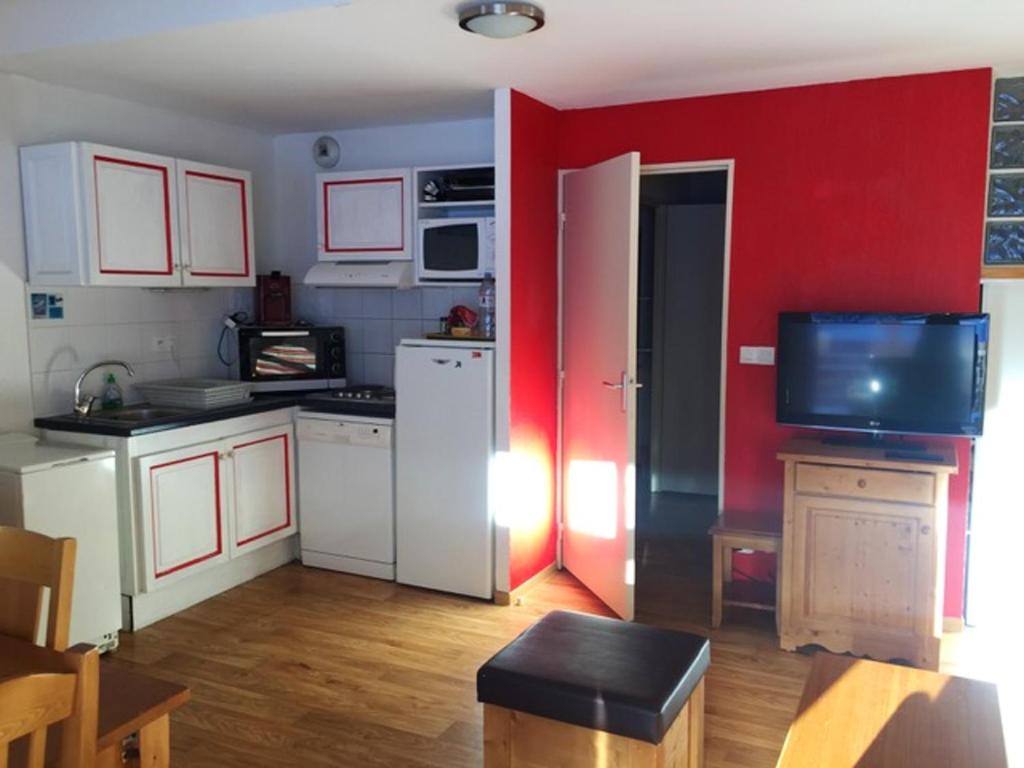 een keuken met een rode muur en een witte koelkast bij Appartement de 2 chambres avec vue sur la ville piscine partagee et terrasse a La foux d'Allos in La Foux